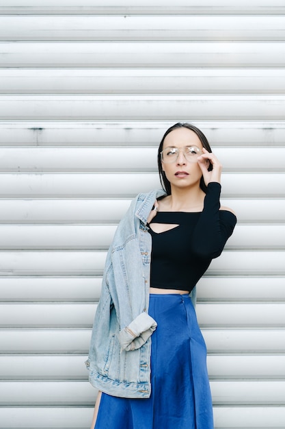 Portrait young woman with glasses. Pretty style woman with long dark hair wearing a denim jacket.