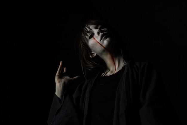 Photo portrait of young woman with halloween make-up against black background