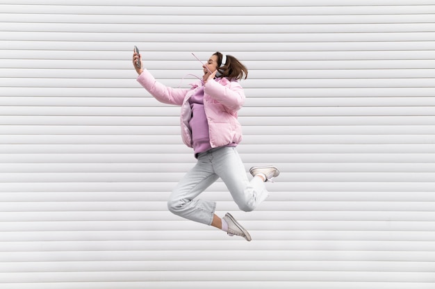 Portrait young woman with headphones jumping