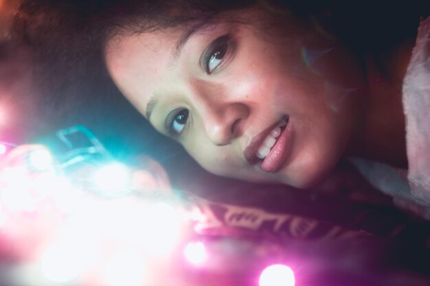 Portrait of young woman with illuminated lights on bed