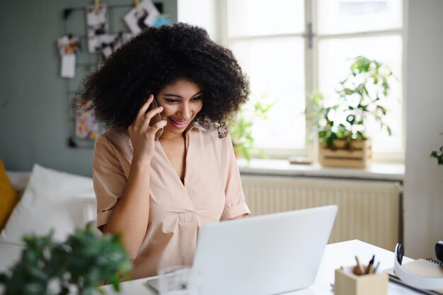 portrait of young woman with laptop and smartphone indoors at home, home office concept.