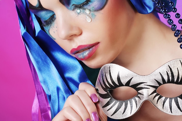 Portrait of young woman with mask in creative theatrical image