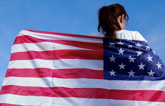 portrait of a young woman with the national flag of the usa on her shoulders