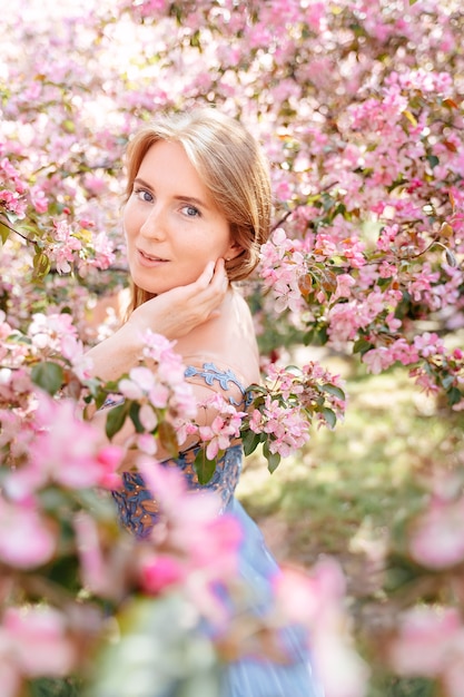 Ritratto di una giovane donna con pelle bianca naturale con capelli rossi sullo sfondo di un giardino di rose ciliegie