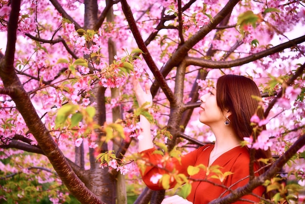 Foto ritratto di una giovane donna con fiori di ciliegio rosa in primavera