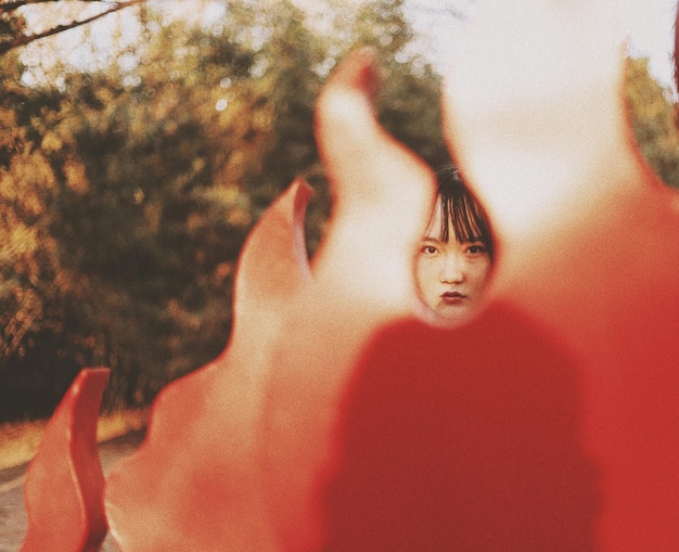 Photo portrait of young woman with red built structure in foreground outdoors