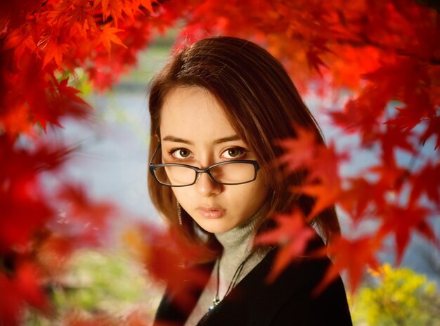 Portrait of young woman with red leaves during autumn