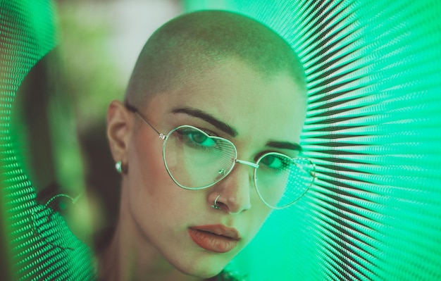 Photo portrait of young woman with shaved head standing against abstract backgrounds