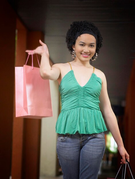 Portrait of young woman with shopping bag standing outdoors