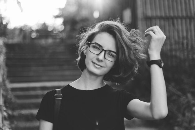 Portrait of a young woman with a short haircut and glasses outdoors