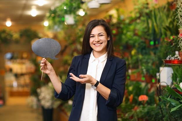 Portrait of young woman with sign in greenhouse Small business owner