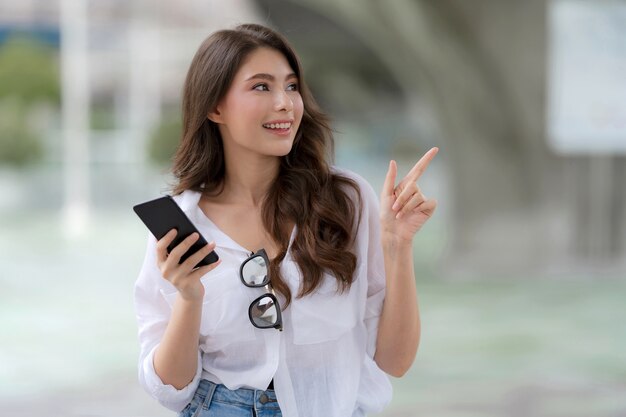 Ritratto di giovane donna con faccina sorridente utilizzando un telefono cammina in una città