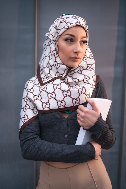 Photo portrait of an young woman with a white veil at the computer on the terrace of a coffee shop