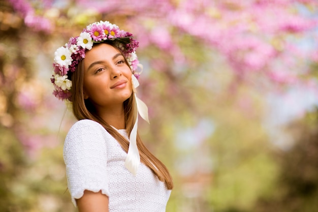 頭の上の新鮮な花の花輪を持つ若い女性の肖像画