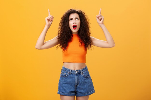 Portrait of young woman with yellow hair against orange background