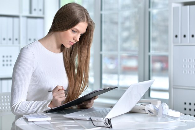 Портрет молодой женщины, работающей в офисе с помощью ноутбука