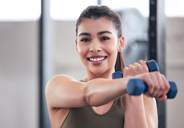 Portrait of a young woman working out with dumbbell weights in a gym