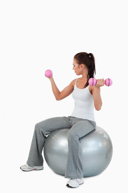 Portrait of a young woman working out with dumbbells and a ball