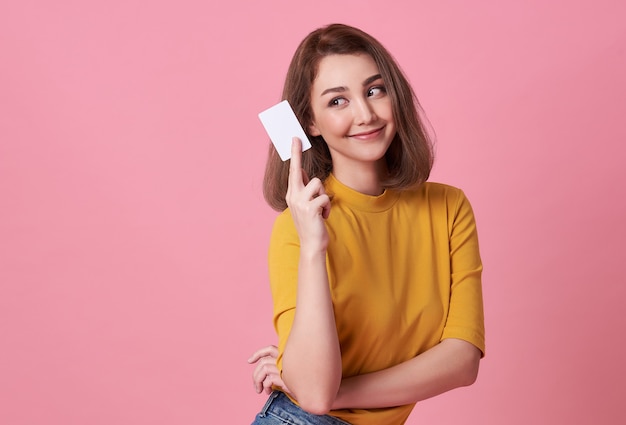 Ritratto di una giovane donna in camicia gialla che mostra una carta di credito