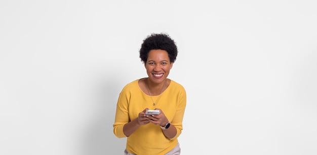 Portrait of young woman in yellow tshirt smiling and chatting over cellphone on white background