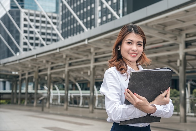 美しいアジアの女性の肖像画は明るく見え、自信は屋外に立っています