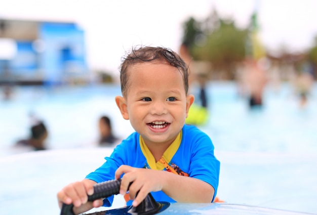 Portraits of happy little Asian baby boy smiling having fun at swimming pool outdoor.