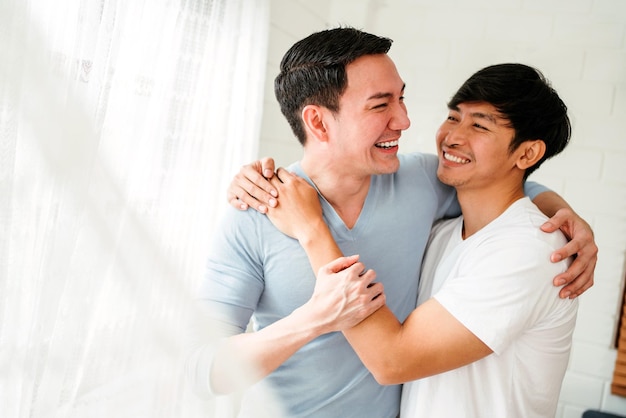 Portraits of happy millennial Asian gay couple hugging and embracing smiling and laughing