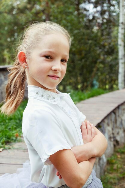 A portraits of a little girl with gathered blonde hair on a summer day in the park