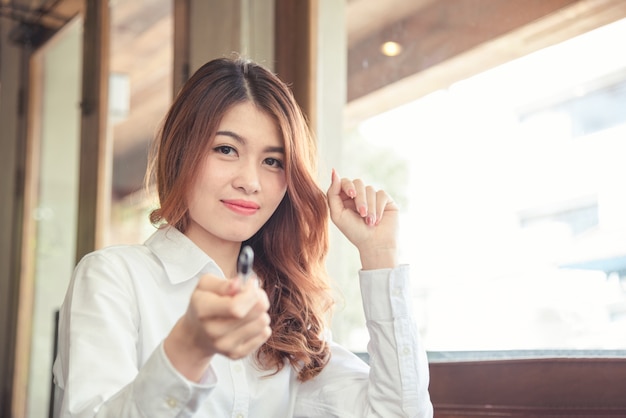 写真 美しいアジアの女性の肖像画は陽気で見て、自信はペンを持っている