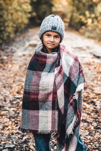 Portrarait of little girl covered in plaid in the autum, Stylish bow