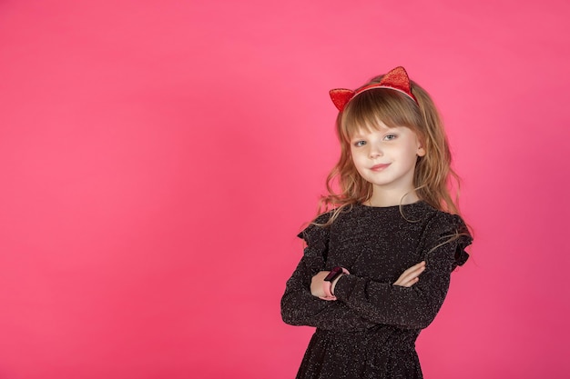 Foto portret 6-7 jaar oud meisje in zwarte jurk op roze geïsoleerd