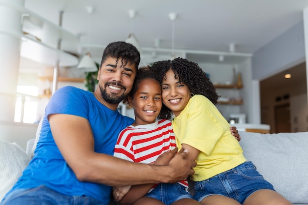 Portret aantrekkelijke multi-etnische vrouw man en kind binnenshuis Close-up getrouwd stel met mooie dochtertje zitten samen glimlachen kijken naar camera Concept vriendelijke welzijn gelukkige familie