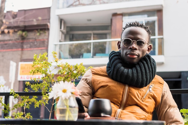 Portret Afrikaanse man zit ontspannen buiten restaurant camera te kijken