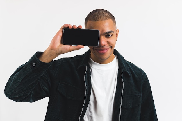 Portret Afro-Amerikaanse man die zijn oog bedekt met smartphone met leeg scherm