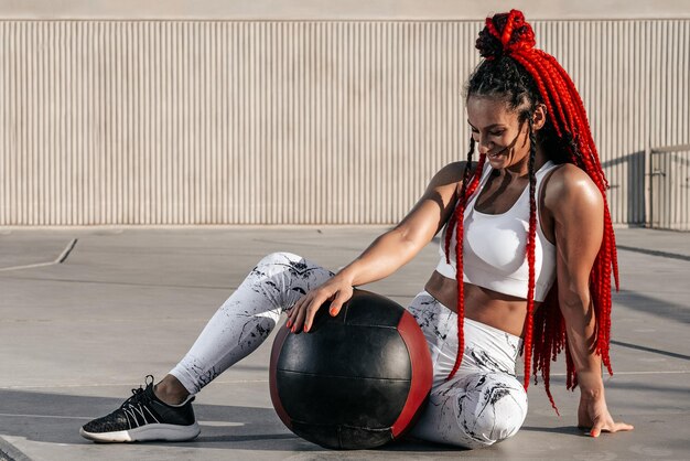 Portret Atletische vrouw doet oefening met med bal Kracht en motivatie Foto van sportieve vrouw in modieuze sportkleding