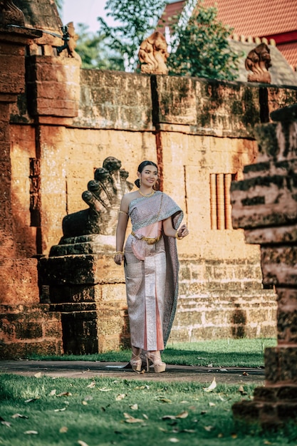 Portret Aziatische charmante vrouw die prachtige typische Thaise kledingsidentiteitscultuur van Thailand draagt in oude tempel of beroemde plaats met gracieus pose