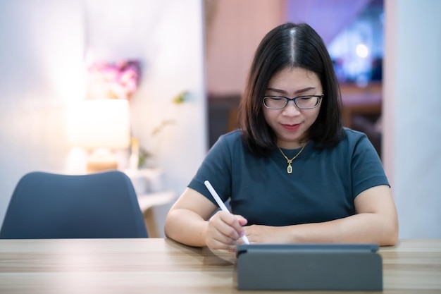 Portret aziatische freelance mensen zakelijke vrouw bril stijlvolle hipster tekenen of notities maken op digitale tablet met elektronische pen voor surfen op internet, chatten en bloggen in coffeeshop