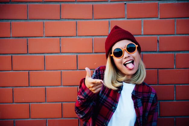 Portret Aziatische hipster meisje op bakstenen muur achtergrond ze dragen oranje zonnebril en rode hoed vintage donkere stijlmode concept