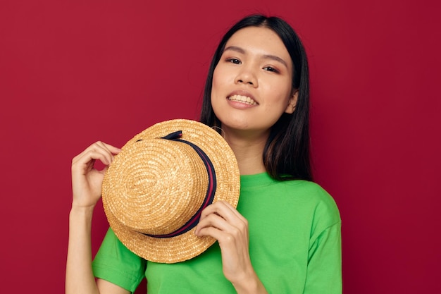 Portret Aziatische mooie jonge vrouw gebaren met zijn handen met een hoed op een groene t-shirt rode achtergrond ongewijzigd