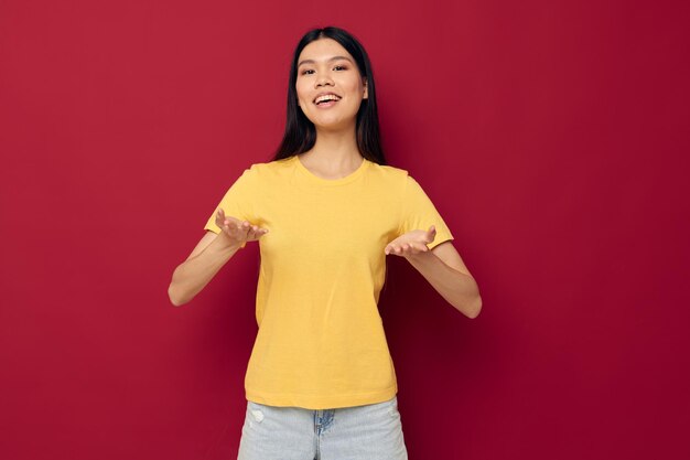 Portret Aziatische mooie jonge vrouw gele casual t-shirt glimlach poseren rode achtergrond ongewijzigd