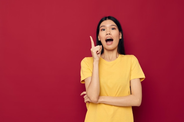 Portret Aziatische mooie jonge vrouw gele casual t-shirt glimlach poseren rode achtergrond ongewijzigd