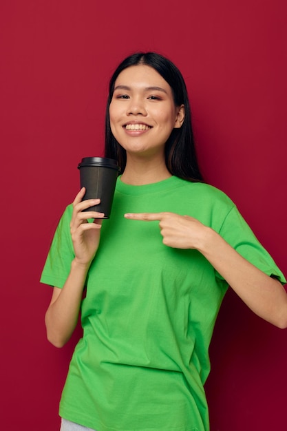 Portret Aziatische mooie jonge vrouw in een groene t-shirt een glas drank plezier geïsoleerde achtergrond ongewijzigd