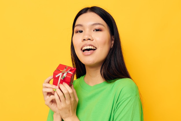 Portret Aziatische mooie jonge vrouw met een kleine geschenkdoos vakantie gele achtergrond ongewijzigd