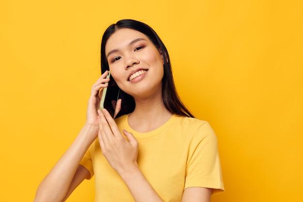 Portret aziatische mooie jonge vrouw telefoon communicatie leuk gebruik gele achtergrond ongewijzigd