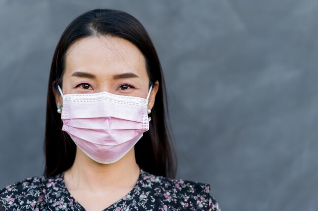 Portret Aziatische vrouw dragen gezichtsmasker met kale cement oppervlak