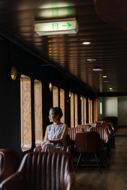 Portret Aziatische vrouw zittend op een leren stoel naast het raam wegkijkend