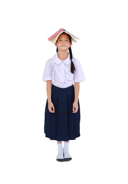 Portret Aziatische weinig schoolmeisje in Thaise schooluniform staande met open tekstboek over hoofd geïsoleerd op een witte achtergrond. Volledige lengte met uitknippad