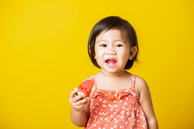 Portret baby meisje lach glimlach houdt gesneden watermeloen vers om te eten