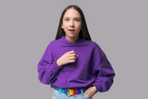 Portret behoorlijk verrast meisje met handgebaar gekleed in paars