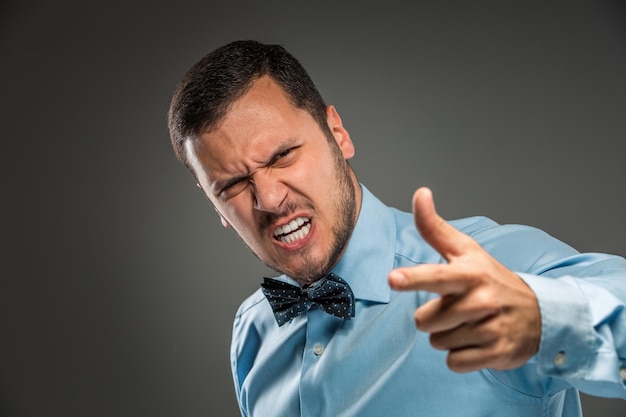 Portret boos overstuur jonge man in blauw shirt, vlinderdas